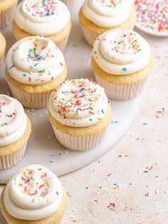 cupcakes with white frosting and sprinkles on a plate