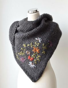 a gray knitted shawl with flowers on the front and side, sitting on a mannequin head