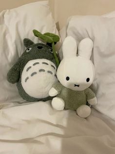 two stuffed animals sitting on top of a bed