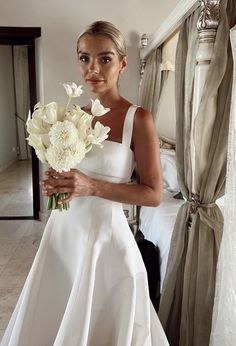 a woman in a white dress holding a bouquet of flowers