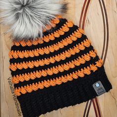 an orange and black knitted hat sitting on top of a wooden table