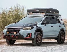 the front end of a light blue subarunt vehicle parked on a dirt road