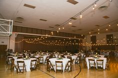 tables and chairs are set up in the middle of a large room with lights hanging from the ceiling