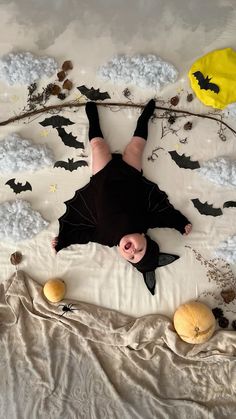 a person laying on top of a bed with bats and pumpkins around them in the air