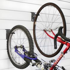 a bicycle hanging from the side of a white wall with a red and blue bike attached to it