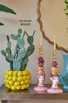 three colorful vases are sitting on a table with cacti and succulents