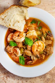 a white plate topped with soup and bread next to a piece of bread on top of a table