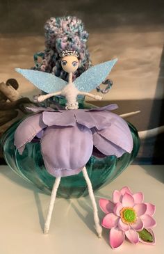 a glass vase with a fairy on it next to a flower