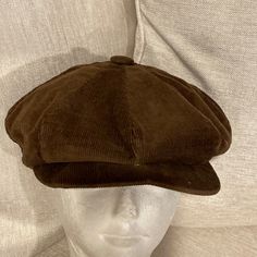 a white mannequin head wearing a brown corded hat on top of it