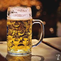 a mug filled with beer sitting on top of a wooden table