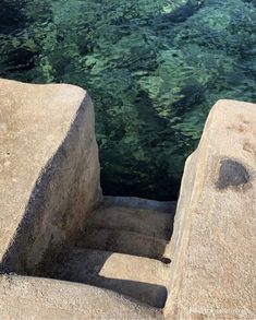 the water is crystal clear and green in this photo, as well as some concrete steps leading up to it