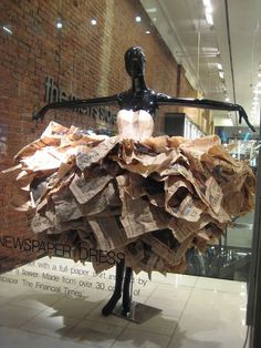 a mannequin made out of newspapers in a store window