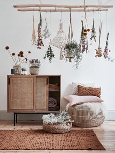 a wicker cabinet with plants hanging from it's sides in front of a white wall