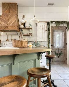 a kitchen with green cabinets and wooden stools