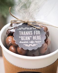 a cup filled with chocolate covered candies on top of a wooden table next to a sign that says thanks for bean here