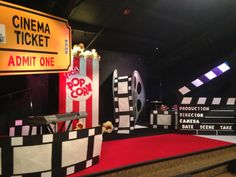 a red carpeted area with claps and movies on the walls, popcorn buckets and movie ticket signs