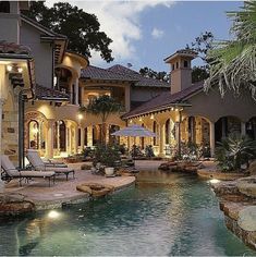 a large house with a pool in front of it and some chairs around the pool