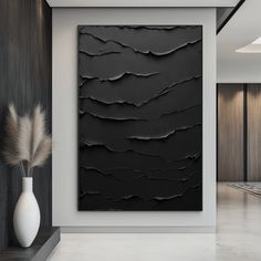 a black and white abstract painting on the wall in a living room with a vase