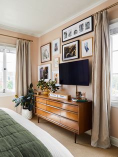 a bed room with a neatly made bed and a flat screen tv mounted on the wall