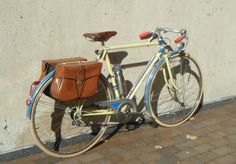 a bicycle parked next to a wall with a bag on it's front rack