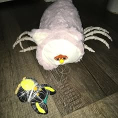 a stuffed animal laying on the floor next to a pair of shoes and a spider toy