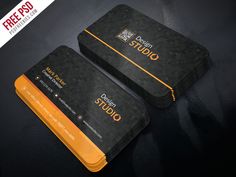 two black and orange business cards sitting on top of a dark surface with the words design studio