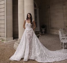 a woman standing in front of a building wearing a wedding dress