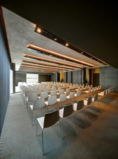 an empty conference room with rows of chairs and lights on the ceiling is lit by recessed lighting