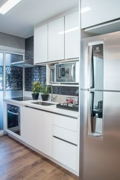 a modern kitchen with stainless steel appliances and wood flooring is pictured in this image