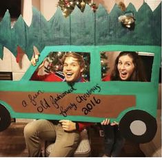 two people holding up a cardboard christmas truck