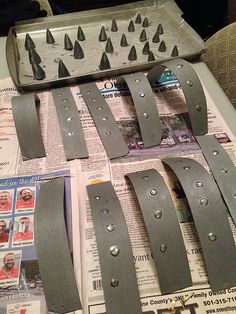 several pieces of metal sitting on top of a table next to newspapers and magazines with nails sticking out of them