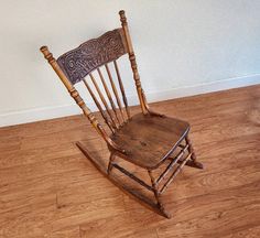 a wooden rocking chair sitting on top of a hard wood floor