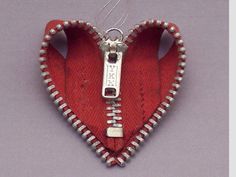 a red heart shaped ornament hanging from a silver chain on a gray background