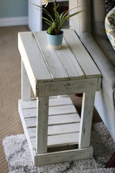 a small table with a potted plant on top of it next to a couch