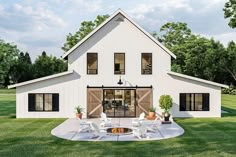 a large white house with a fire pit in the front yard and two chairs around it