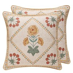 two embroidered pillows with flowers on them, one is white and the other is orange