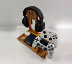 two video game controllers sitting next to each other on a wooden stand with headphones