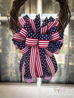 a patriotic wreath on a window sill with an american flag bow hanging from it