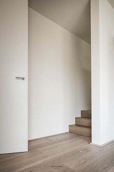 an empty room with white walls and wood flooring on the bottom level is shown