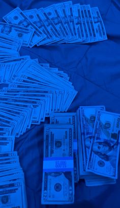 a pile of money sitting on top of a blue bed cover covered in paper currency