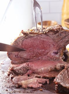 a large piece of meat is being cut into pieces with a knife on top of it