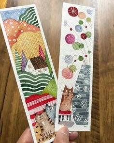 two handmade bookmarks with cats and balloons on them, one is holding the other