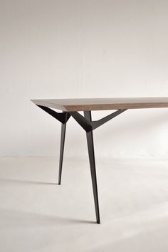 a wooden table sitting on top of a white floor next to a black metal frame