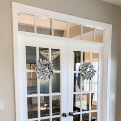 two glass doors with wreaths on them in a home entryway, surrounded by hardwood flooring