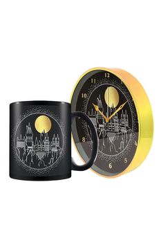 a black and yellow coffee mug sitting next to a clock with an image of a castle on it