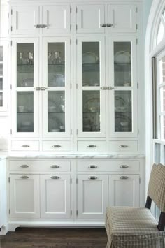 a white china cabinet with glass doors and drawers