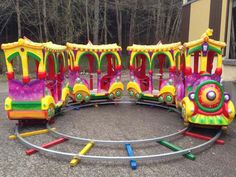 a colorful toy train sitting in the middle of a parking lot