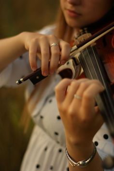 a woman is playing the violin outside