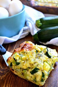 an egg and zucchini casserole on a cutting board with a bowl of eggs in the background