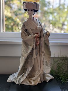 a geisha doll sitting in front of a window